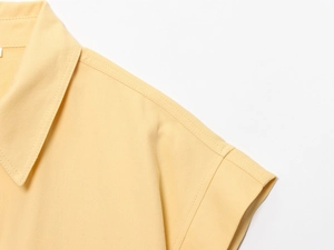 Vue détaillée du col de chemise en coton jaune vif et des coutures doubles nettes