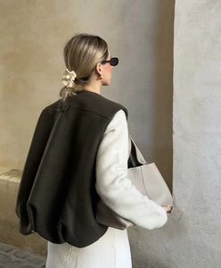 Back view of a casual olive green vest styled with a white plush top and a chic beige handbag
