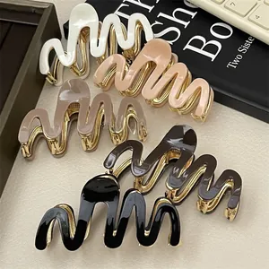 Close-up of wavy acetate hair claws in cream, pink, brown, and black with gold bases