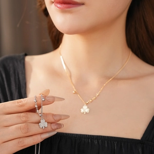 Model wearing gold clover pendant necklace and silver bead bracelet jewelry set