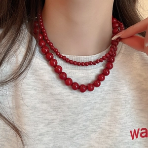 Double-layered vibrant red glass bead necklace shown worn on a model neckline