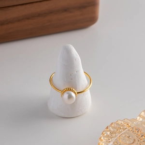 Detailed view of an elegant gold ring featuring a large white freshwater pearl on a cone stand