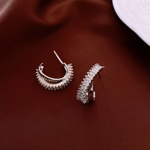 Close-up of silver hoop earrings with rectangular cubic zirconia on red velvet