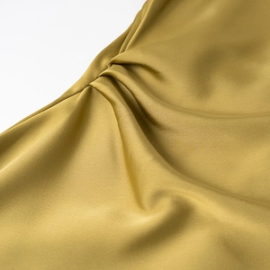 Detailed macro view of mustard yellow satin fabric showing smooth texture and elegant drapes