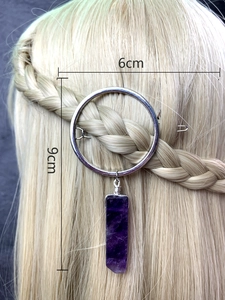 Detail view of a 6cm round silver hair clip with a purple crystal pendant on braided hair