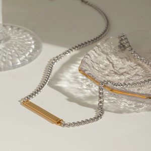 Close-up of a silver cuban chain with a gold rectangular bar pendant in a chic setting