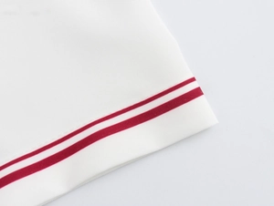 Close-up of white fabric with red parallel stripes and detailed stitching on the hemline