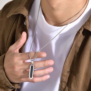 Detail view of men's geometric silver necklace with black pendant on male model