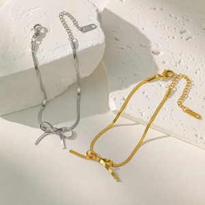 Detail showing gold and silver bowknot snake chain necklaces on white stone blocks