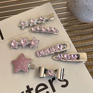 Close-up of seven pink rhinestone hair clips with star and bow motifs on a magazine