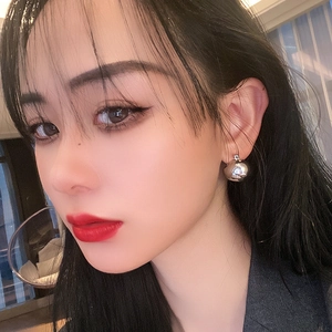 Minimalist silver spherical metal stud earrings for women shown on a model