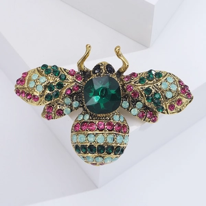 Detail of vintage bee brooch with colorful crystals on a white geometric stand