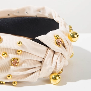 Close-up of beige wide headband with gold beads and sparkling crystal embellishments