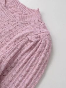 Close-up of hollow knit texture and ribbed crew neck on soft pink knit sweater