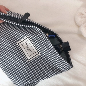 Close-up of black and white houndstooth makeup bag with cosmetics inside the zipper compartment
