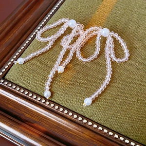 Close-up of pink crystal bead bow earrings with white pearl tassels on a vintage box