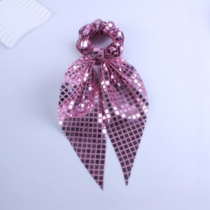 Close-up of pink sequined scrunchie with long ribbon featuring square sparkling patterns