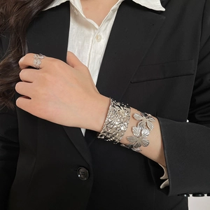 Close-up of silver flower bracelet and hammered metal cuff on model's wrist