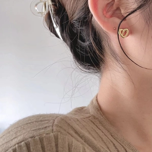 Minimalist hollow heart-shaped gold earrings shown worn on a model's earlobe