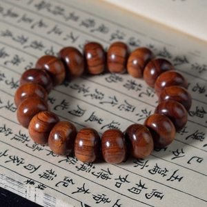 Bracelet en perles de bois de santal poli présenté sur un livre vintage traditionnel