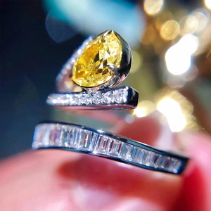 Détail d'une bague avec pierre jaune taille poire et double anneau serti de diamants