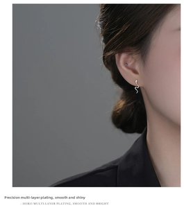 Detail of silver snake stud earring and black ball cuff worn on a model's ear
