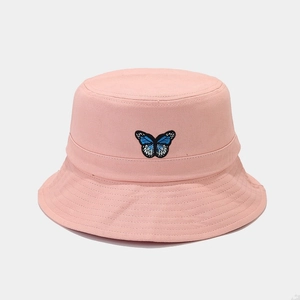 Close-up of a pink bucket hat featuring detailed blue butterfly embroidery on the front