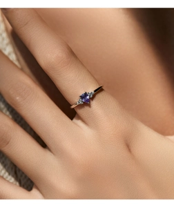 Detail of rose gold ring with pear-shaped purple gemstone and accent diamonds on hand