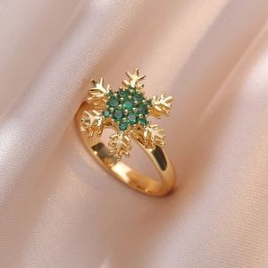 Bague flocon de neige dorée avec zircons vert émeraude sur tissu de soie rose