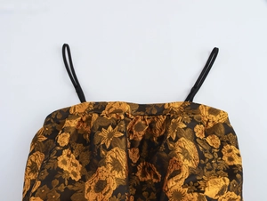 Dettaglio del tessuto jacquard floreale dorato con sottili spalline nere su un crop top