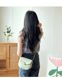 Détail du sac selle vert menthe avec boucle cœur dorée porté par un mannequin