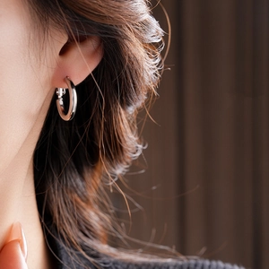 Close-up of a minimalist silver hoop earring with smooth polished finish on a model