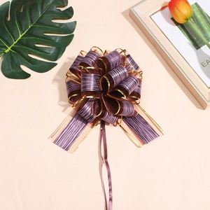 Close-up of elegant purple and gold mesh ribbon bow with long streamers on a desk