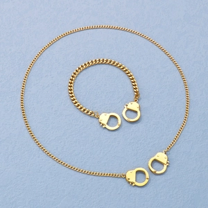 Detailed view of golden Cuban link necklace and bracelet set with handcuff design