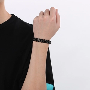 Gros plan d'un bracelet gourmette noir en acier inoxydable poli porté au poignet masculin