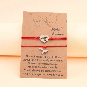 Detail of red braided dinosaur couple bracelets on card with romantic English vow text