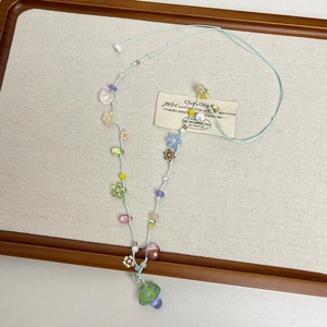Detail view of flower necklace with colored beads and mushroom pendant on wooden tray
