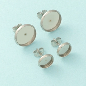 Macro shot of silver stainless steel stud earring bases in two sizes on blue background