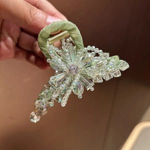 Detail of green ribbon hair claw clip featuring faceted crystal beads and center rhinestone