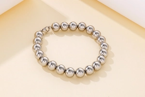 Detail of silver beaded bracelet with lobster clasp on minimal geometric display