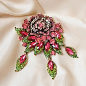 Detail of baroque rose brooch with pink rhinestones and green leaves on silk