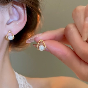 Detailed view of elegant teardrop-shaped gold pearl earrings worn on a female model