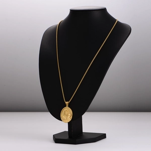Vintage gold oval embossed religious portrait pendant necklace on a black display stand