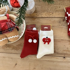 Detailed view of red and white Christmas knit socks with pom-poms and festive bows