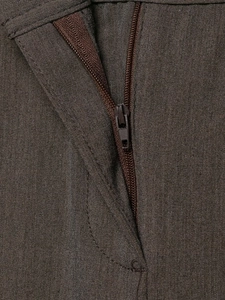 Détail d'un ensemble en tissu marron avec une fermeture éclair en nylon et des coutures fines