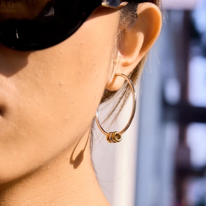 Detail von goldenen Creolen mit ineinandergreifenden Ringen, getragen von einem Modell