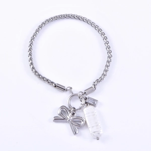 Detailed view of silver bow charm, baroque pearl and crystal on stainless steel chain