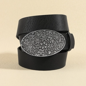 Close-up of black faux leather belt with vintage floral engraved silver metal buckle
