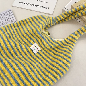 Detail der blau-gelb gestreiften Plüsch-Tragetasche mit besticktem Patch und weicher Textur