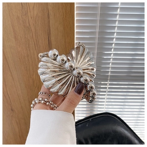 Detail of silver shell clutch bag with metallic finish and large pearl embellishments